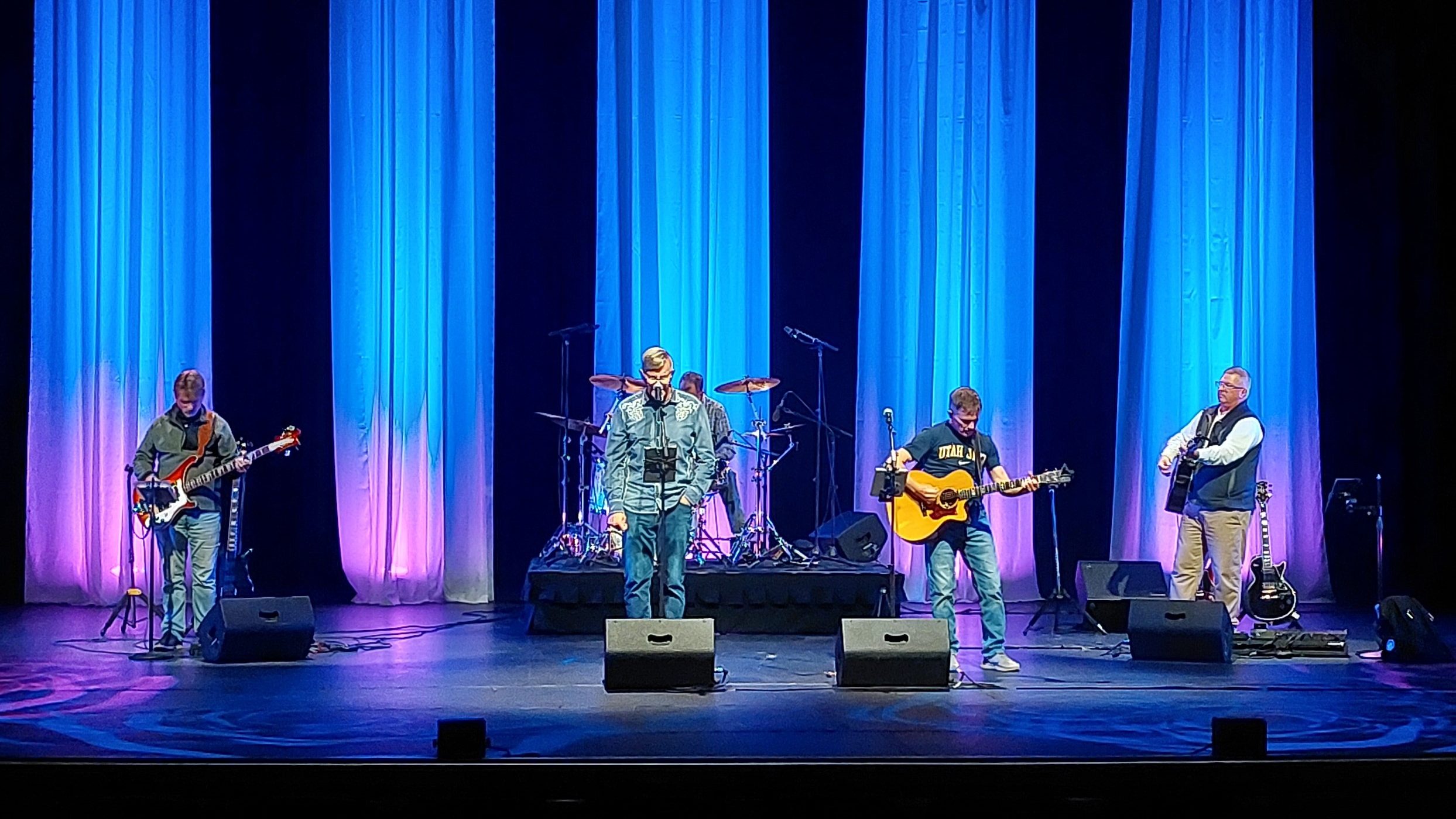 A band on a light stage performing for an audience