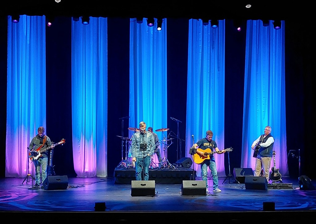 A band on a light stage performing for an audience