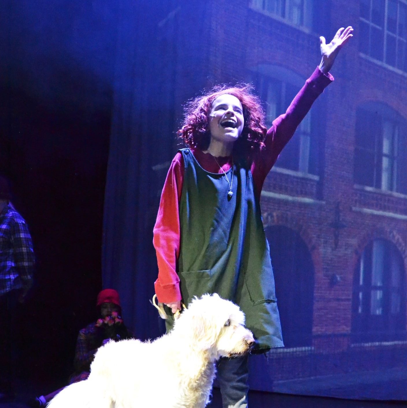 Annie singing a solo with a fluffy dog standing next to her